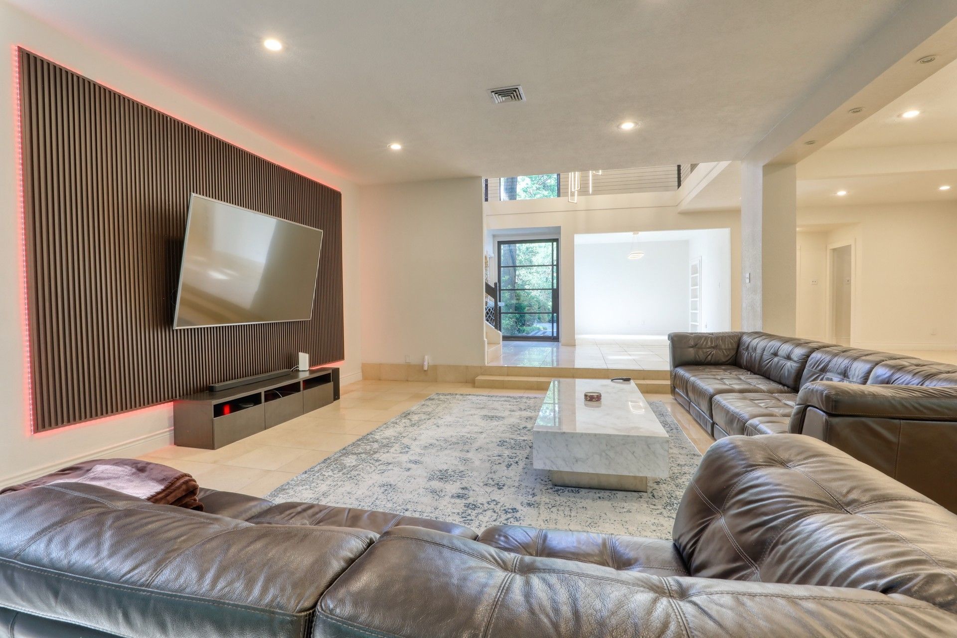 Living room with leather sectional and wood-slat TV wall