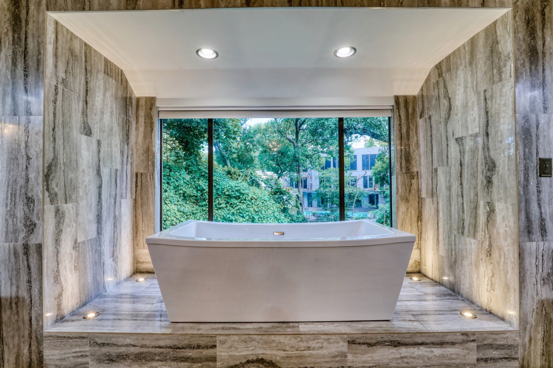 Freestanding soaking tub facing a floor-to-ceiling window