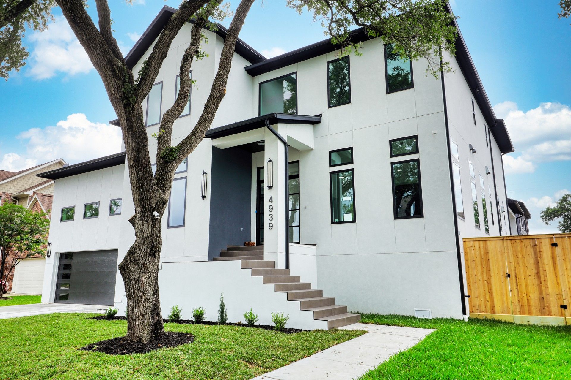 Front exterior of a modern home with a mature oak tree